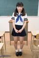Standing in class hair in pigtails hands clasped together wearing uniform