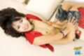 On her back smiling broadly pulling shorts down