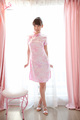 Standing in front of window wearing pink cheongsam high heels