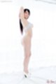 Standing beside curtained window arms raised wearing bra bare ass high heels
