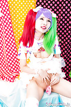 Seated with legs spread holding lollipop between her legs bald pussy