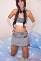 Kneeling on bed hands on hips stripey top hair in pigtails short skirt